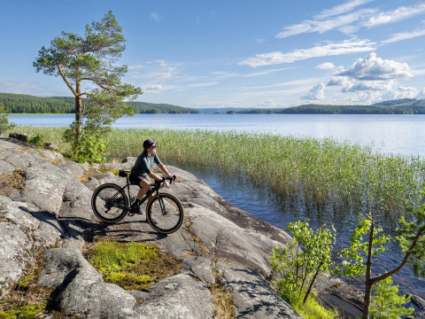 Pyöräilijä rantakalliolla kesällä, taustalla järvi. Kuva Markus Kirchgessner