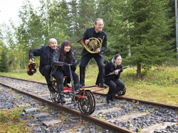 Neljä tumma-asuista muusikkoa instrumentteineen ajavat resiinalla. Kuva Jiri Halttunen