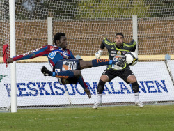 Kaksi jalkapallon pelaajaa. Oikealla on maalivahti torjumassa ja vasemmalla JJK:n pelaaja potkaisemassa pallon maaliin. Kuva Risto Aalto