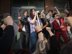 Rort-yhtye promokuvassaan esittää esiintyvänsä yleisölle, yhtye taustalla ja edustalla fanien käsiä nyrkissä kannustamassa yhtyettä. Kuva Anne Kalliola