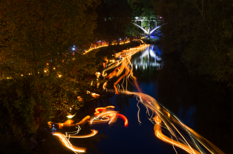tourujoki pimeässä, joen pinnalla valoteoksia sulautuneena valovirraksi, takana valaistu silta. Image Juhana Konttinen
